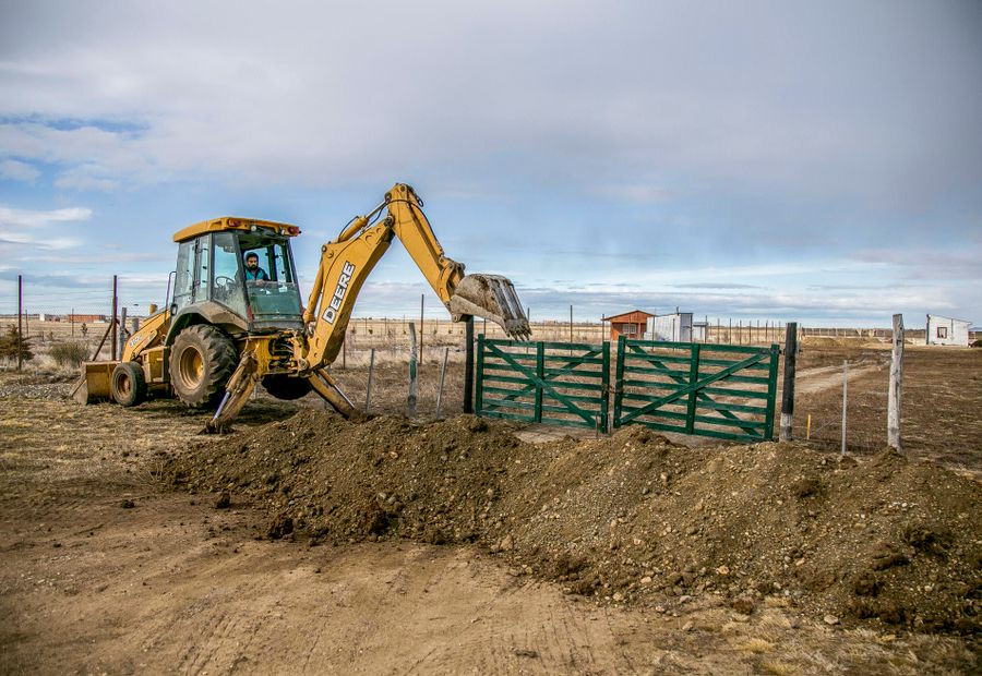 Backhoe digging out an old culvert at a rural field gate entrance